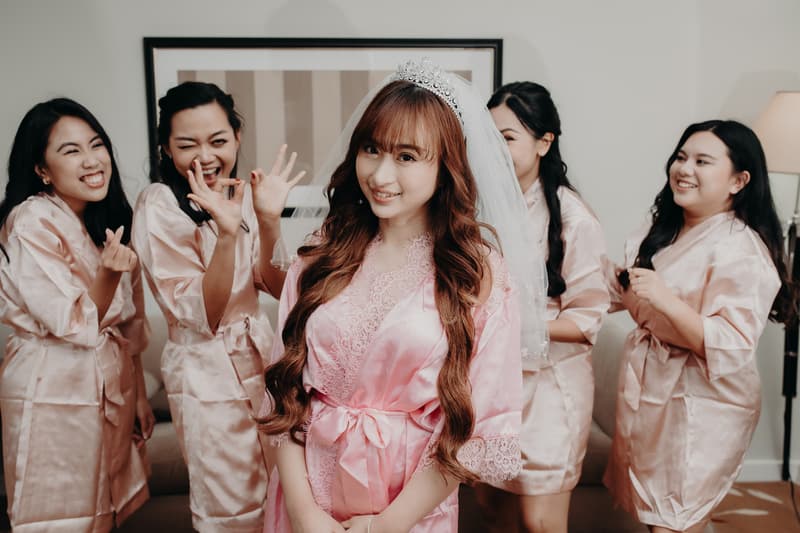 The bride Henny wearing a tiara and veil poses in a pink robe with four bridesmaids in matching pink robes behind her at Royal on the Park.