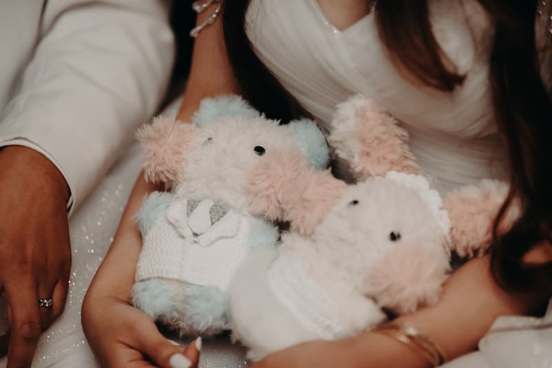 The bride and groom at the reception stage of their wedding at Royal on the Park hold two plush bunny toys dressed in wedding attire.