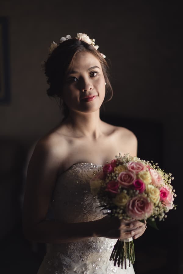The bride Wing poses holding a bouquet of pink and cream roses at Bilinga Beach Weddings.