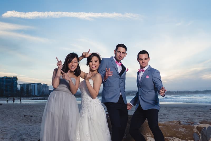 The bride Wing and groom Jason pose with a bridesmaid and a groomsman on the beach at Bilinga Beach Weddings during the couple portraits stage.