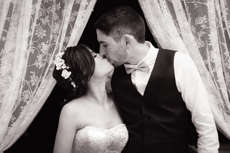 Bride Wing and groom Jason share a kiss framed by lace curtains at Bilinga Beach Weddings — Bilinga SLSC.