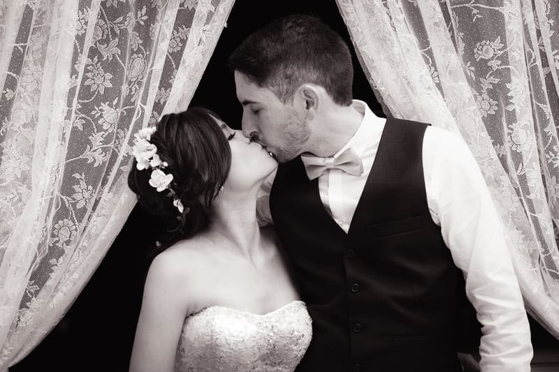 Bride Wing and groom Jason share a kiss framed by lace curtains. Easter long weekend wedding Brisbane by She Said Yes.