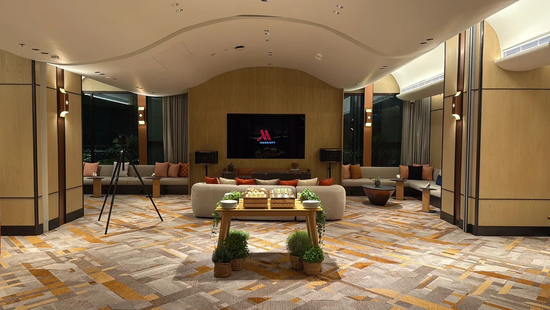Matterport camera capturing a lounge at Chiang Mai Marriott Hotel, with sofas, refreshments and a large screen.