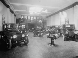 Automobiles on Display in Tent Under American Flag Banners - Art Print