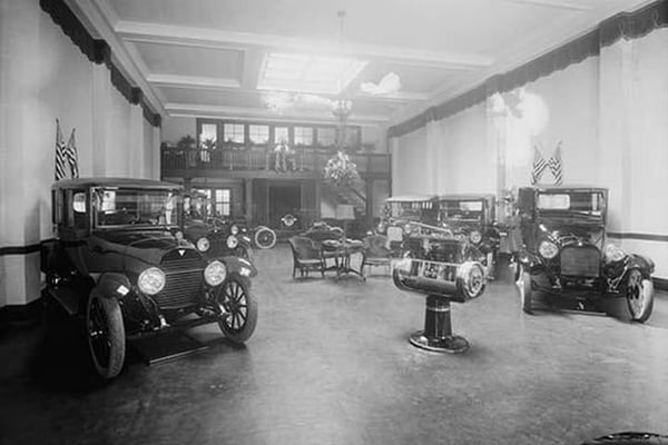 Automobiles on Display in Tent Under American Flag Banners - Art Print
