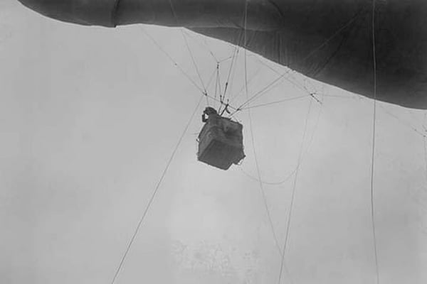 Military Observer hangs from a Balloon by guide wires looking over battlefield - Art Print