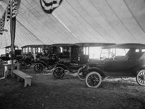 Automobiles on Display in Tent Under American Flag Banners #2 - Art Print