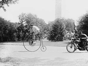 Motorcycle cop chases a Penny Farthing Velocipede down a DC Street with Washington Monument in background - Art Print