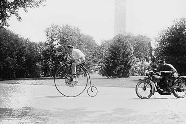 Motorcycle cop chases a Penny Farthing Velocipede down a DC Street with Washington Monument in background - Art Print