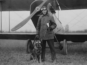 Aviator and His dog wear goggles in front of his Biplane - Art Print