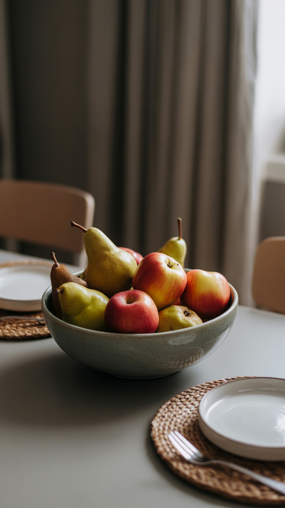 A bowl filled with red apples and green pears on a table