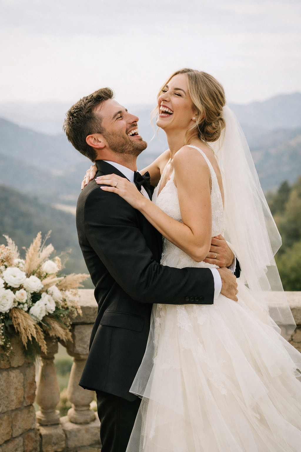 Couple laughing while embracing at a scenic overlook with mountains in the background.