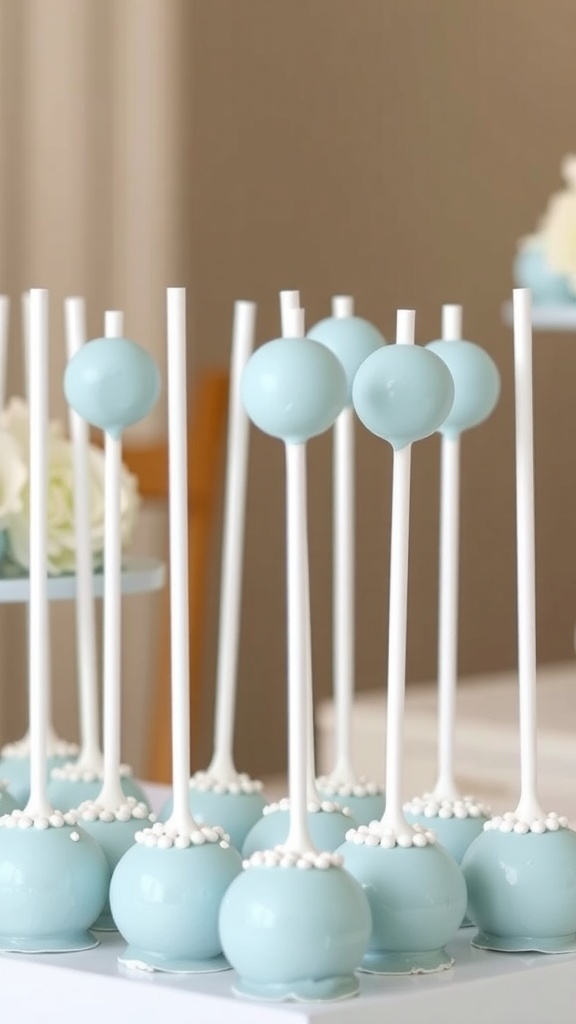 A display of baby blue cake pops on sticks with white decorations, perfect for a bridal shower.