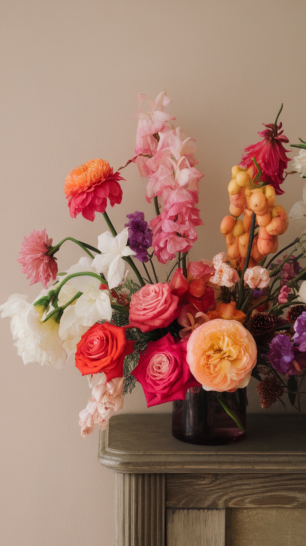A vibrant flower arrangement featuring roses, peonies, and snapdragons in bright colors.