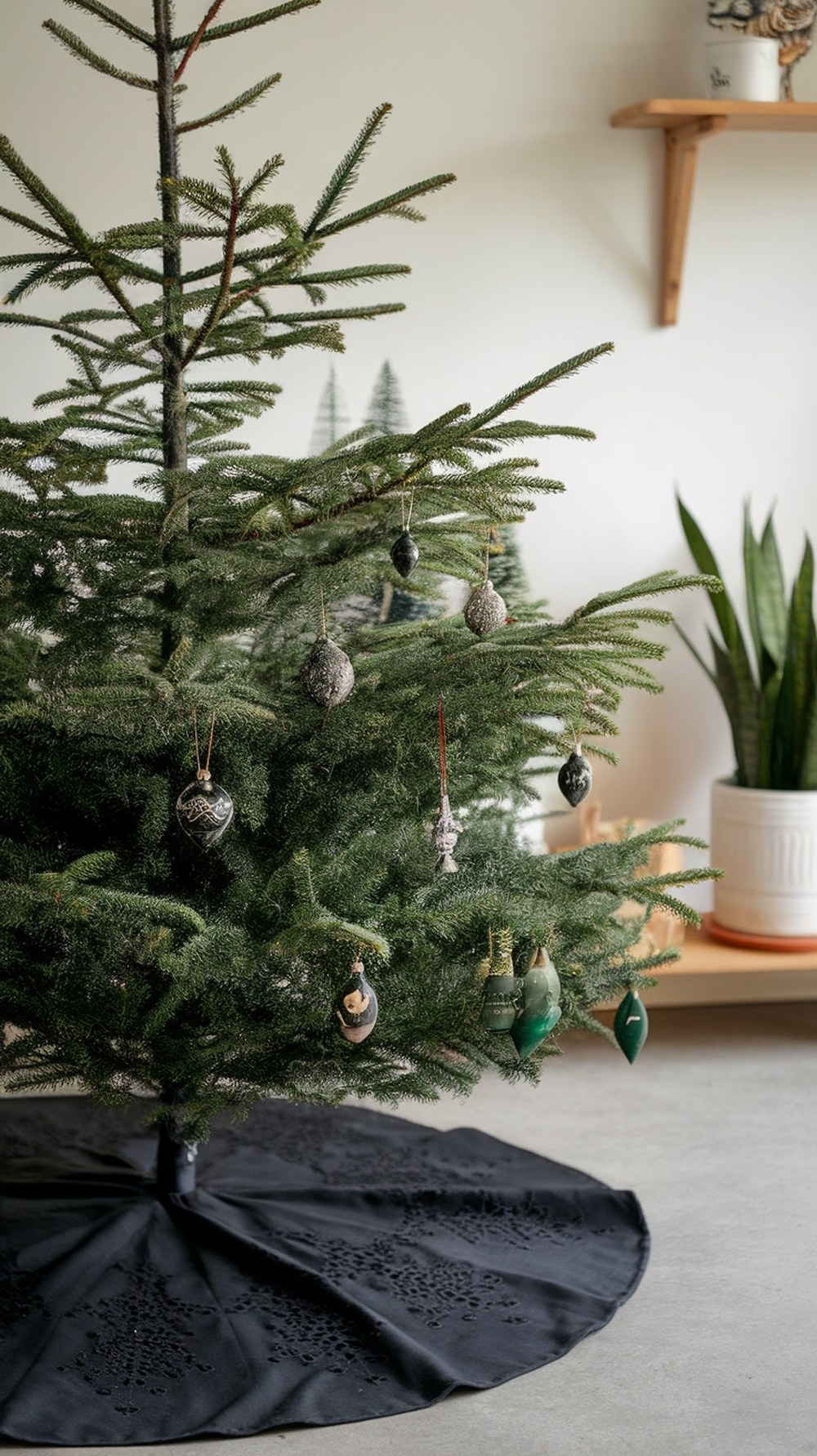A black Christmas tree skirt under a decorated Christmas tree with ornaments.