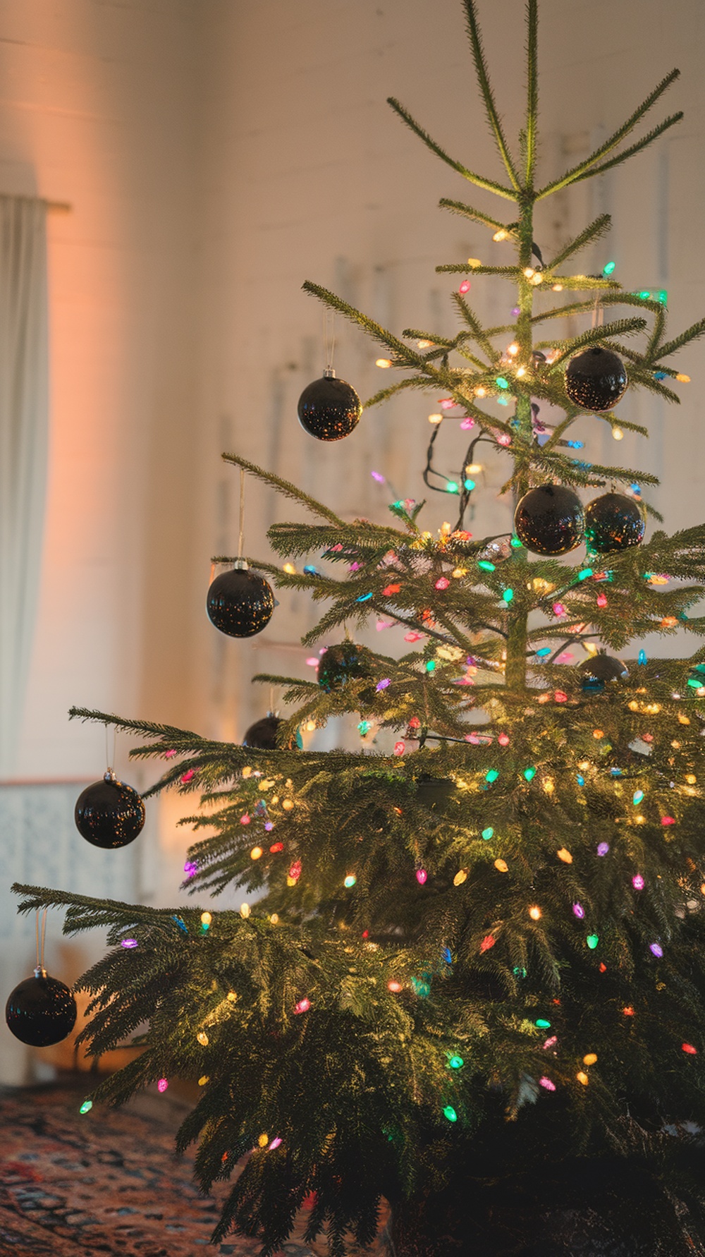 A black Christmas tree decorated with colorful lights and black ornaments.