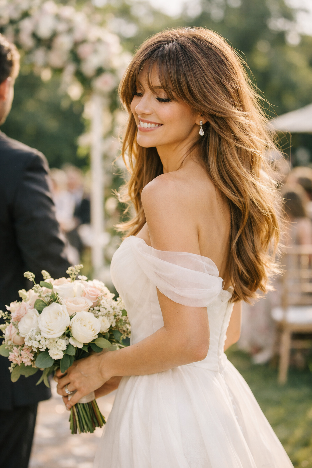 A woman at a wedding, smiling with long layered hair and feathered bangs, holding a bouquet of flowers.