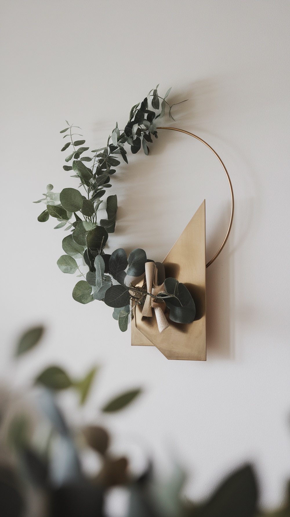 A modern minimalist wreath with eucalyptus leaves and a geometric base.