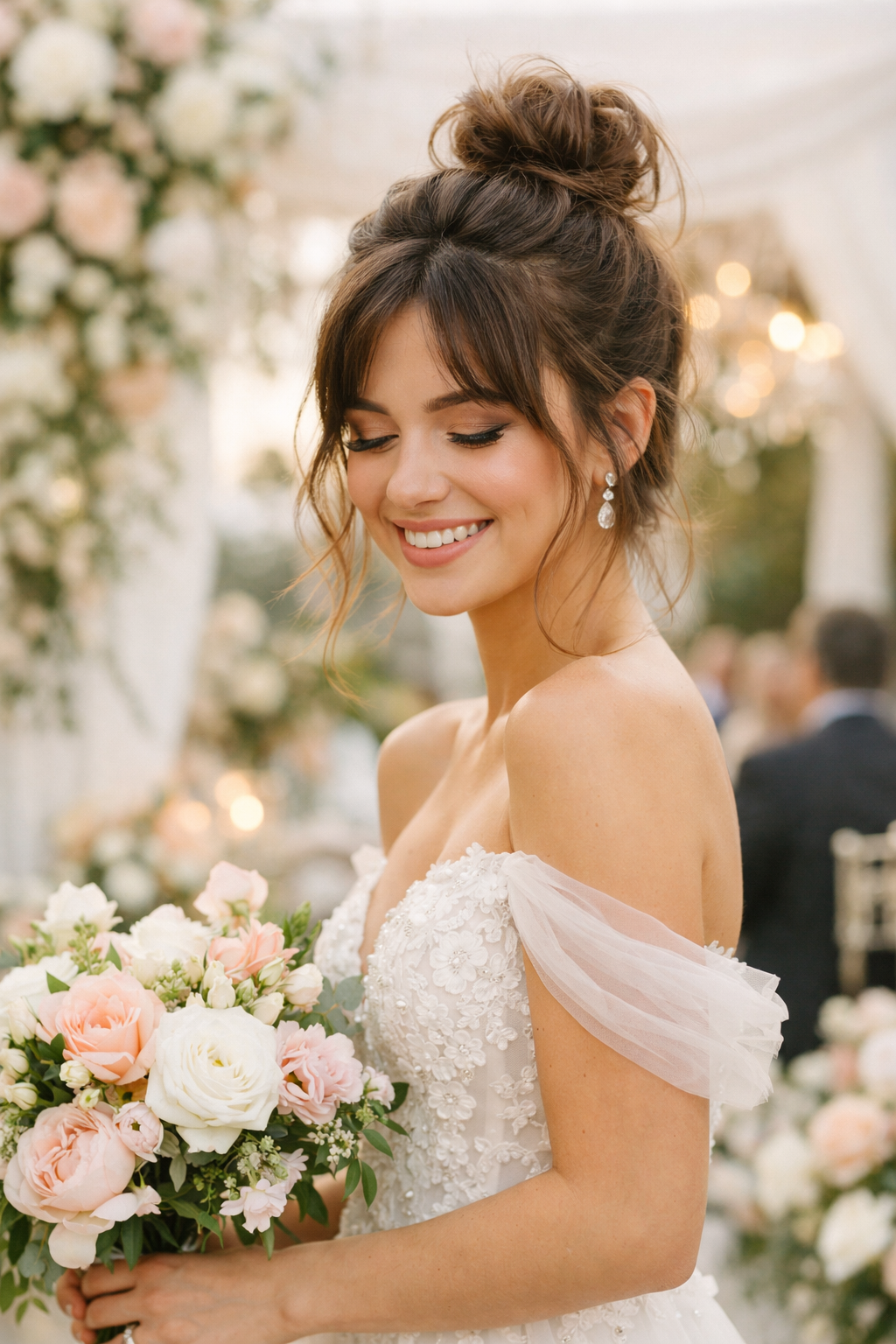 A woman with a playful top knot and tendrils wearing a floral wedding dress, holding a bouquet of flowers.