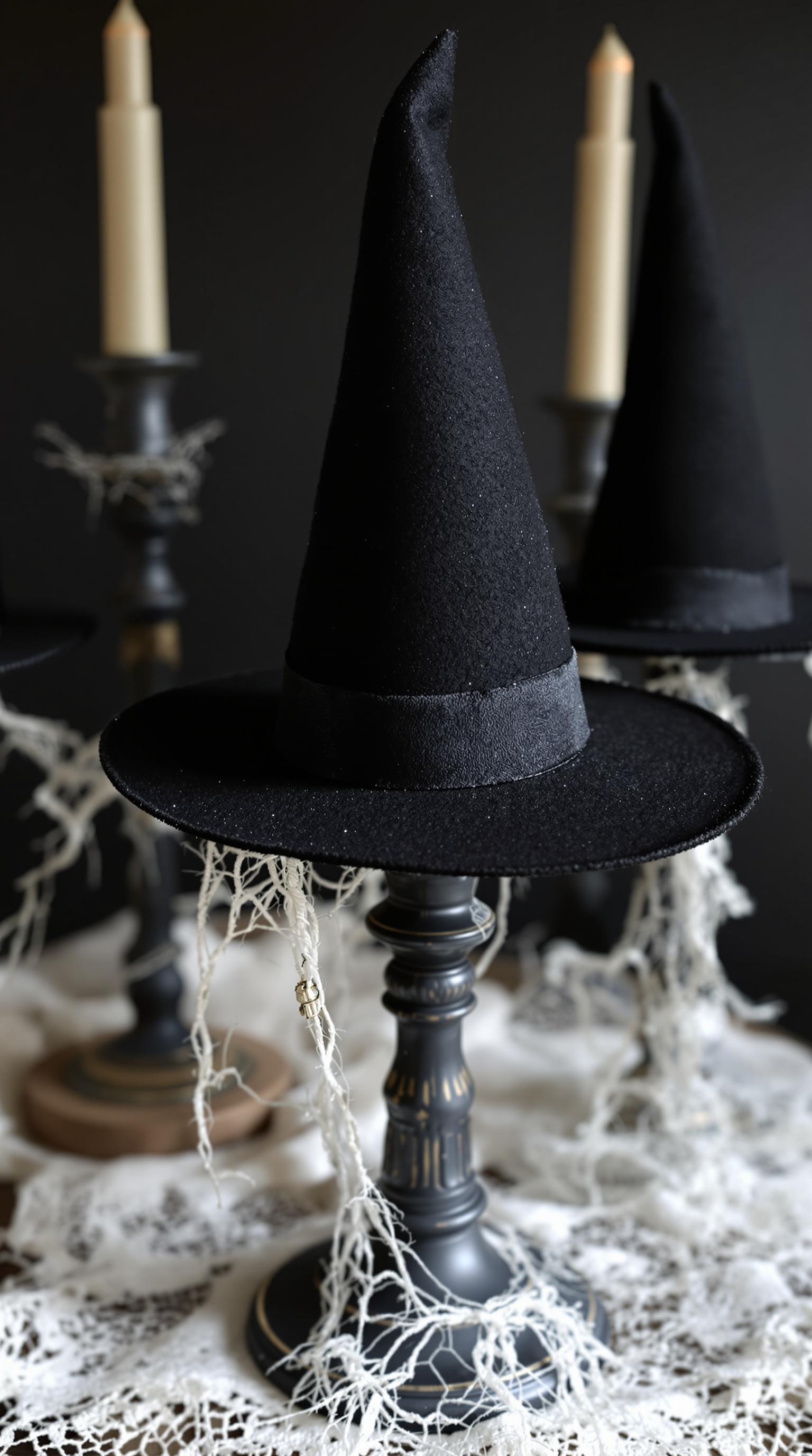Witch hat centerpieces on candle holders with lace and cobweb decorations.