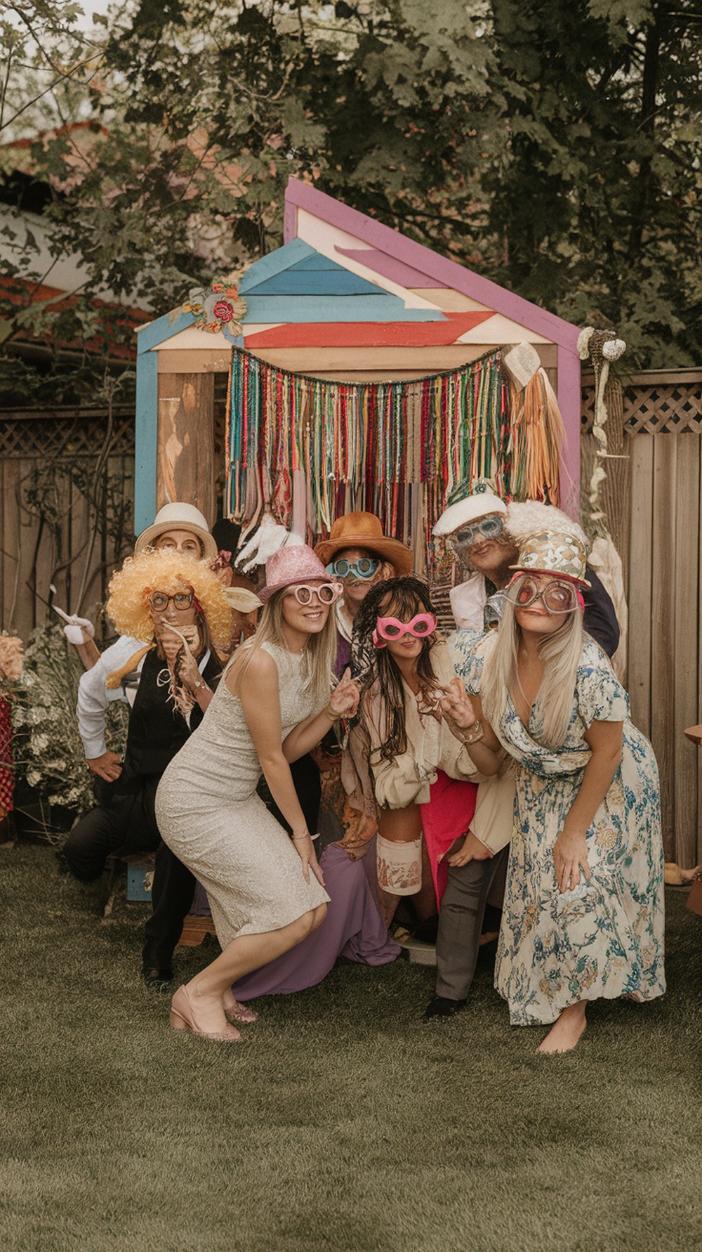A vibrant photo booth corner at a backyard party with colorful decorations and guests posing for pictures.