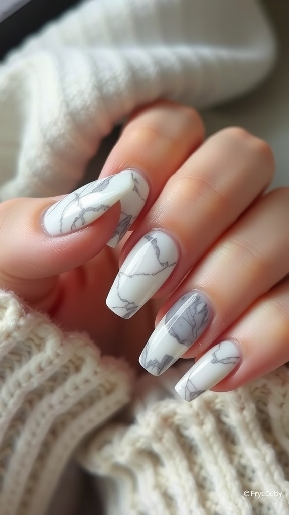 Nails featuring an artistic marble effect in white and gray, set against a cozy knitted background.