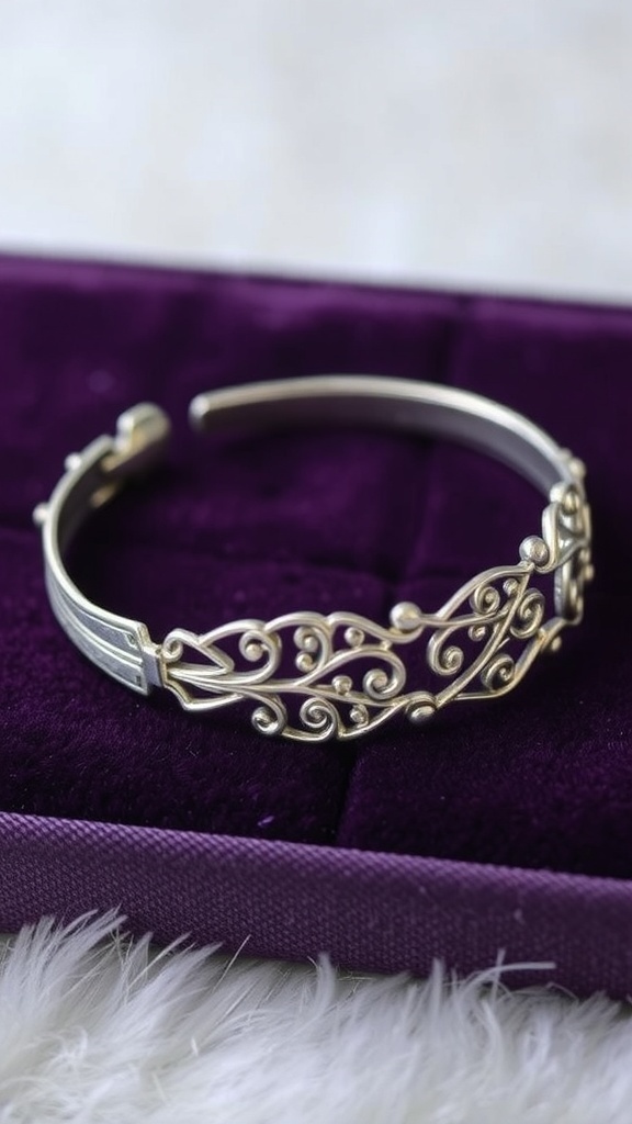 A delicate silver bracelet with intricate filigree patterns displayed on a purple velvet background.