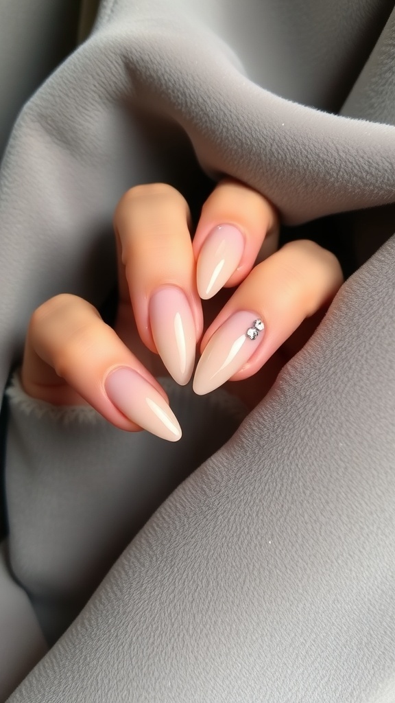 Nude nails with jewel embellishments on a hand, showcasing a stylish and elegant design.