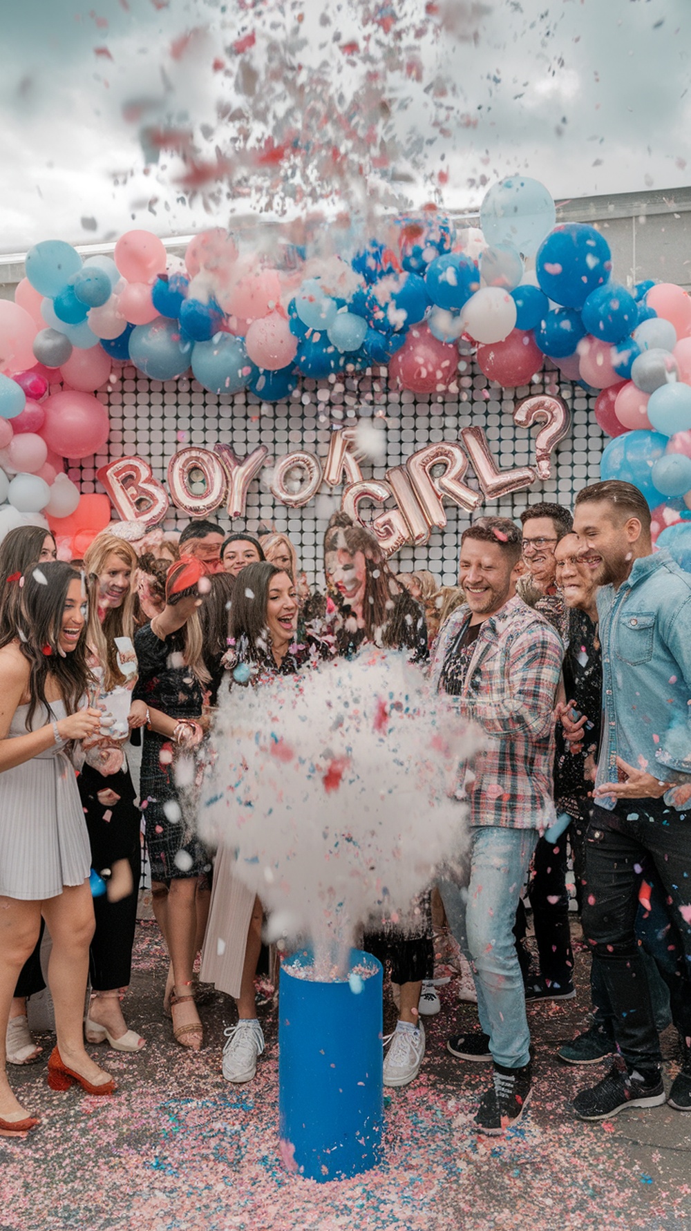 A group of people celebrating a gender reveal with confetti and balloons.