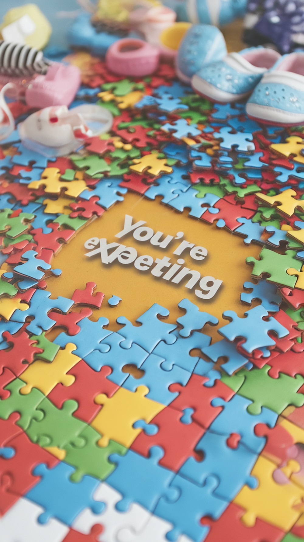 A colorful puzzle with baby shoes and the text 'You're expecting'