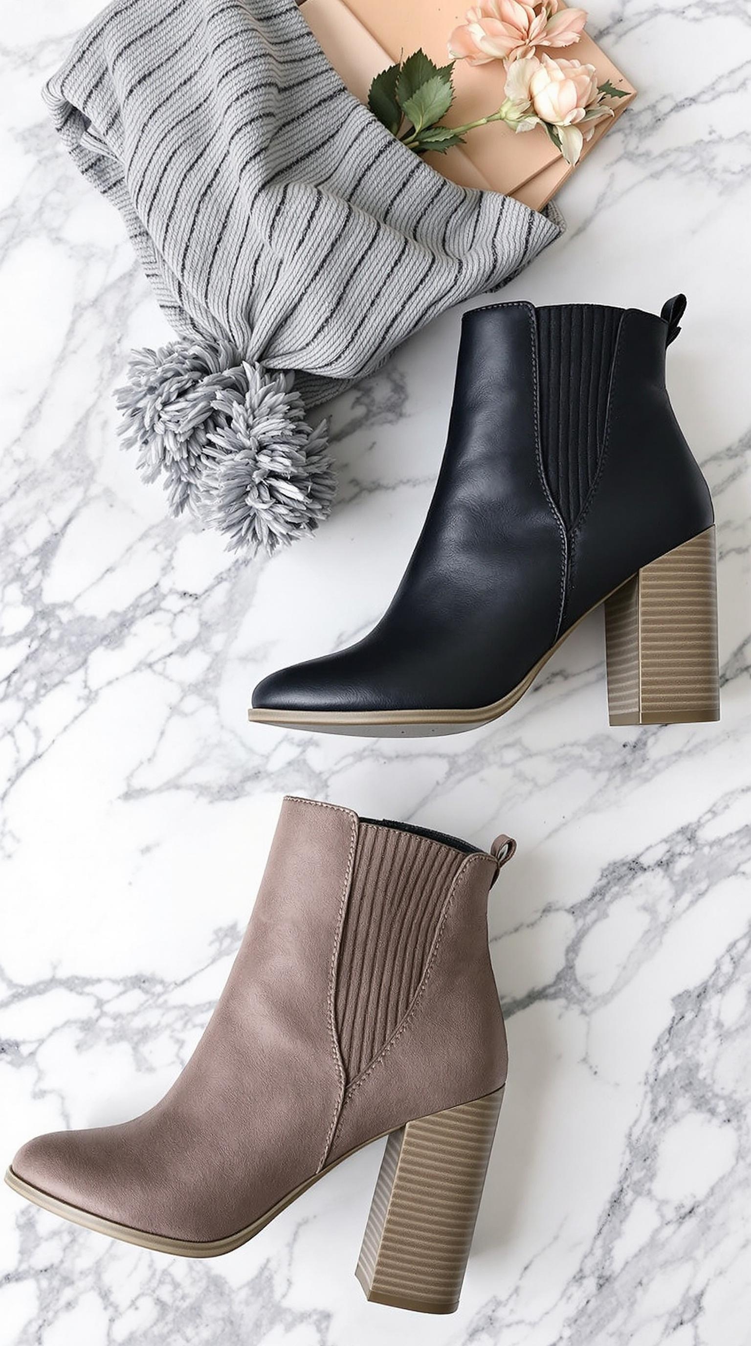 Chic black ankle boots with chunky heels on a marble surface next to a fashion magazine.