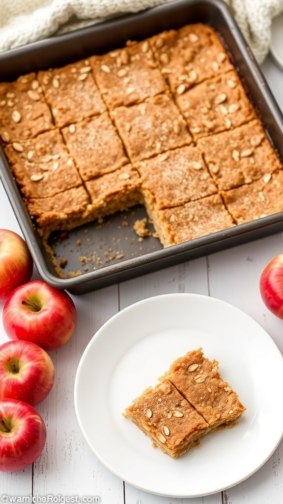 A pan of cinnamon-spiced apple oat bars cut into squares, with fresh apples on the side.