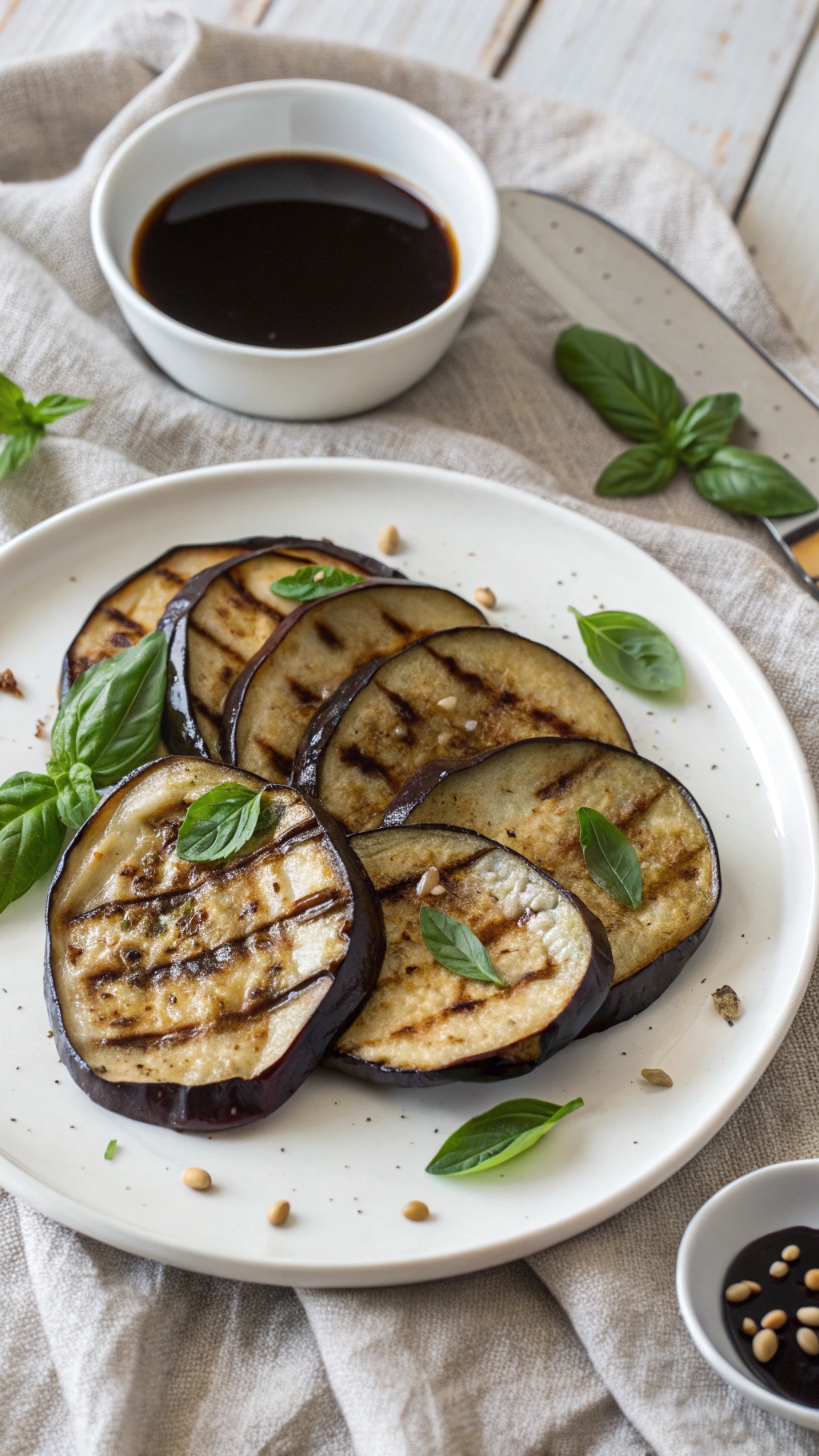 Grilled eggplant slices with balsamic glaze and fresh basil on a plate