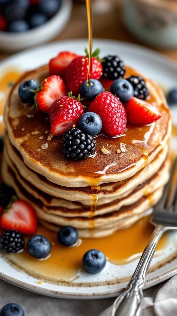 A stack of whole grain pancakes topped with strawberries, blueberries, and blackberries, drizzled with syrup.
