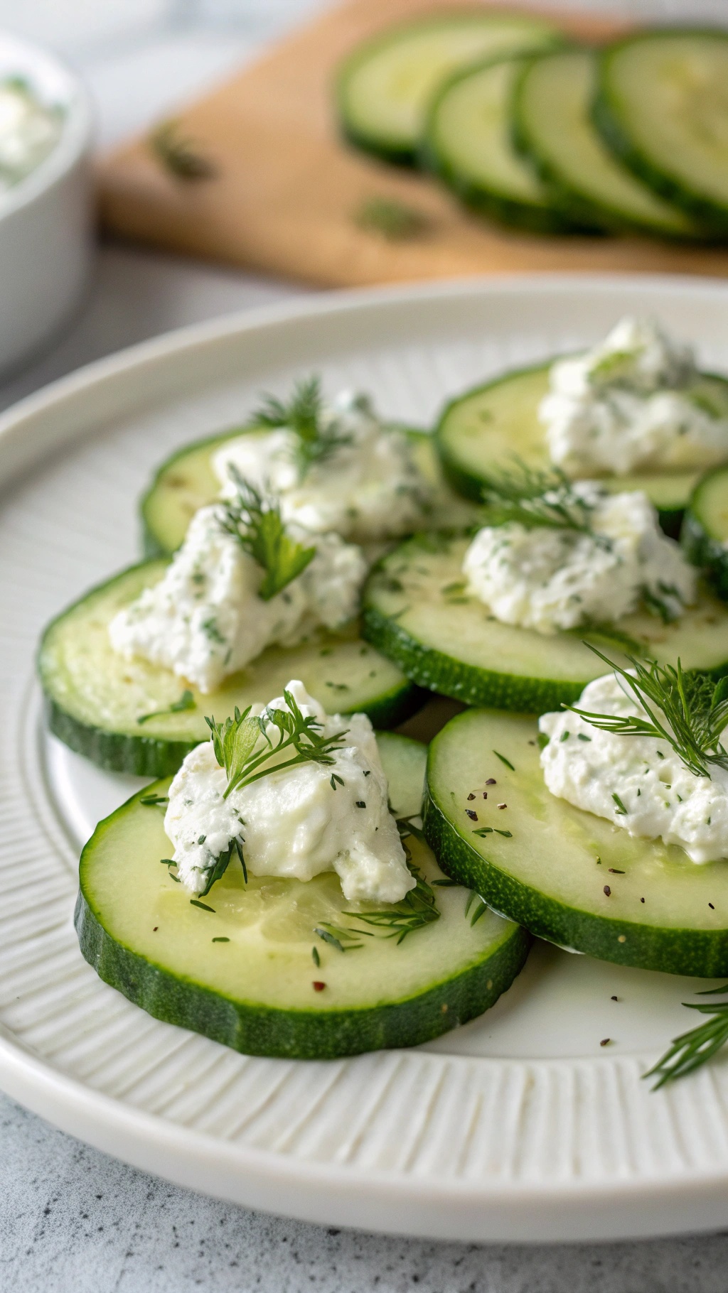 Cucumber slices topped with cream cheese and herbs on a plate