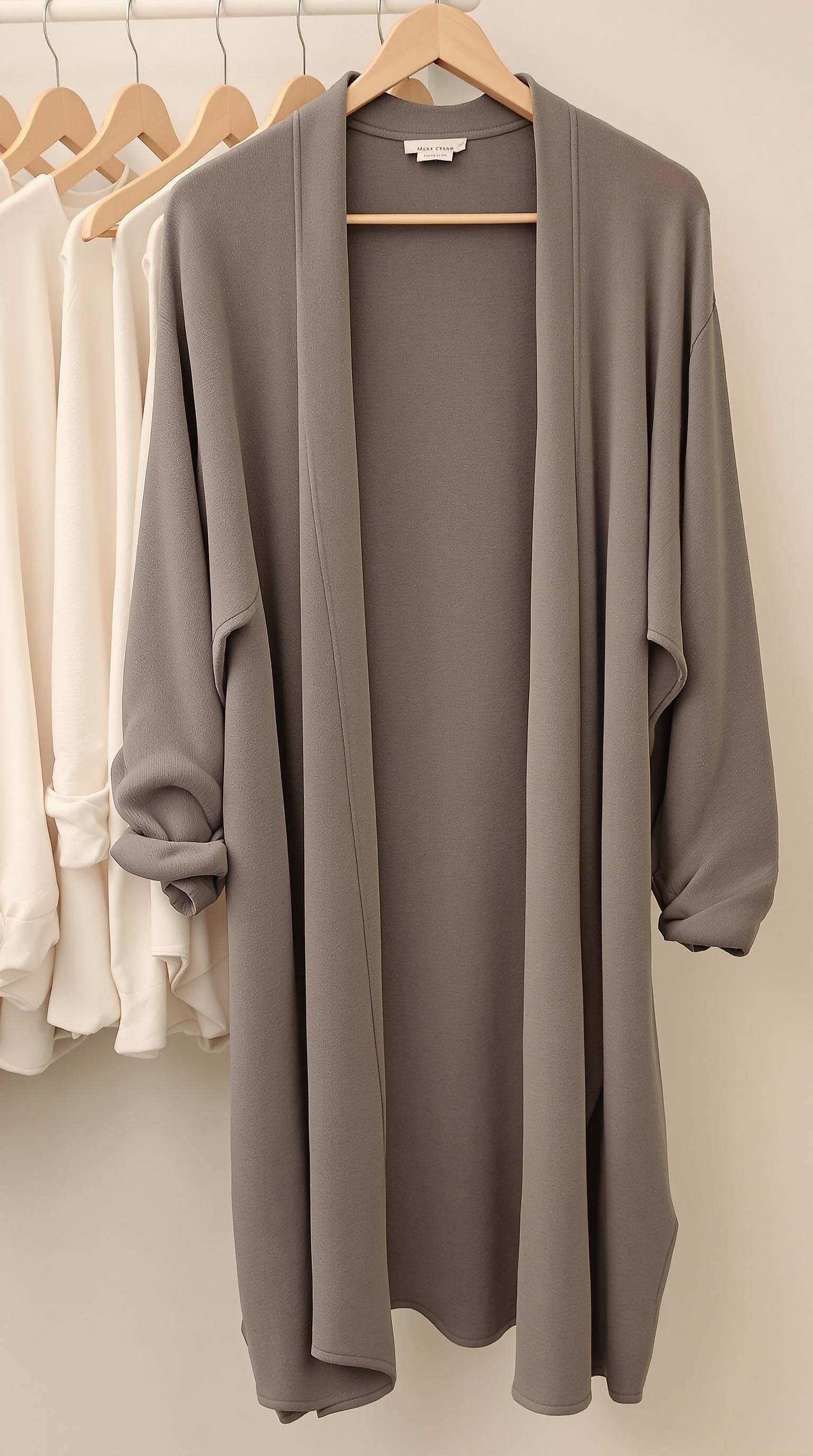 A light-colored open front cardigan hanging on a rack.