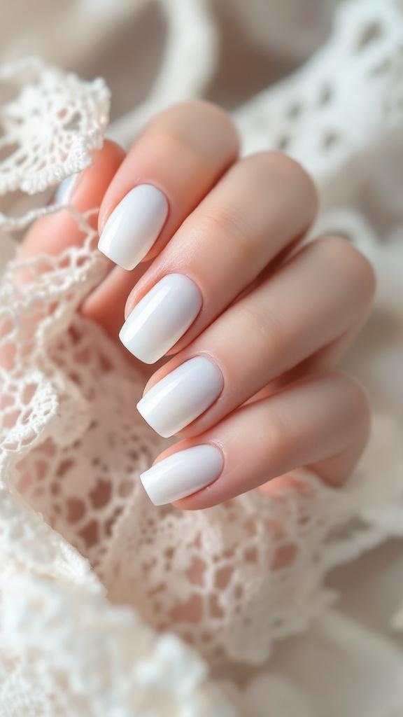 A hand with white ombre fade nails, elegantly displayed against a lace background.