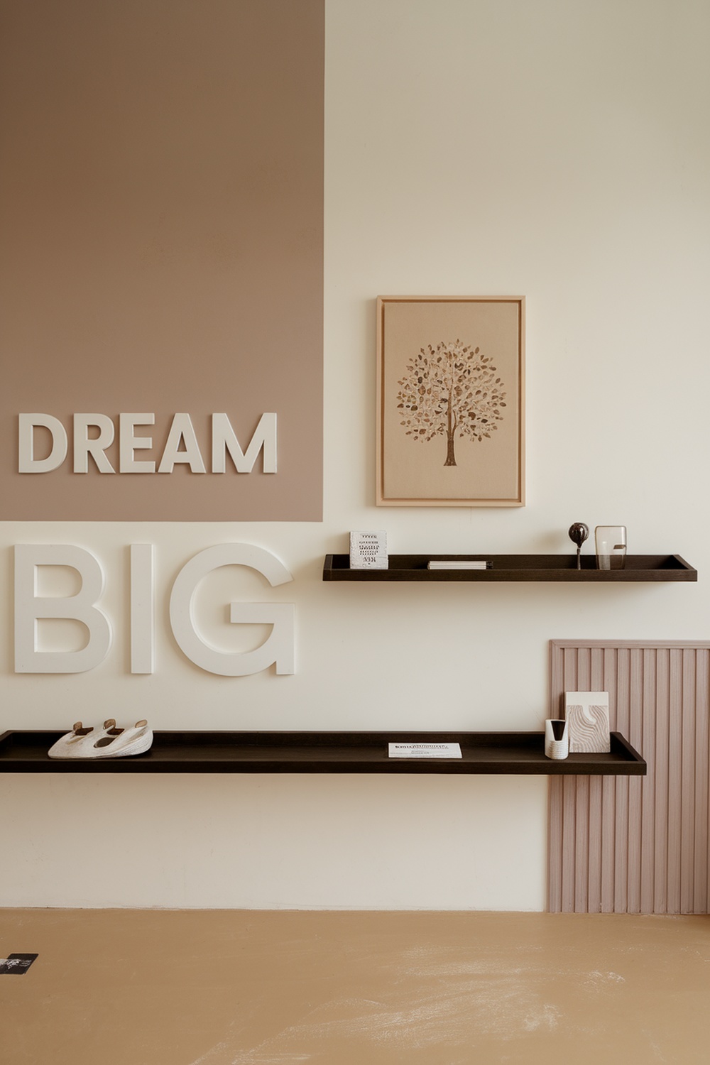 A minimalist home office wall featuring the words 'DREAM BIG' and a tree artwork, with decorative items on shelves.