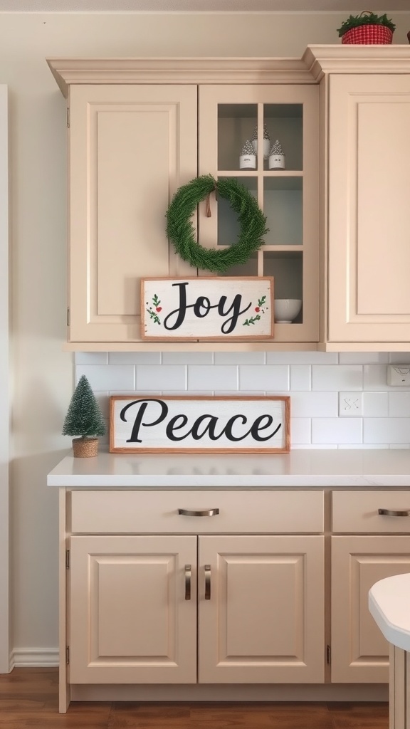 Kitchen cabinet decorated with signs saying 'Joy' and 'Peace' along with a wreath and a small tree.