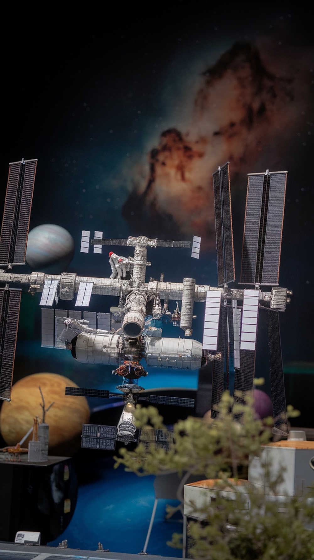 A detailed miniature model of a space station in orbit with planets in the background.