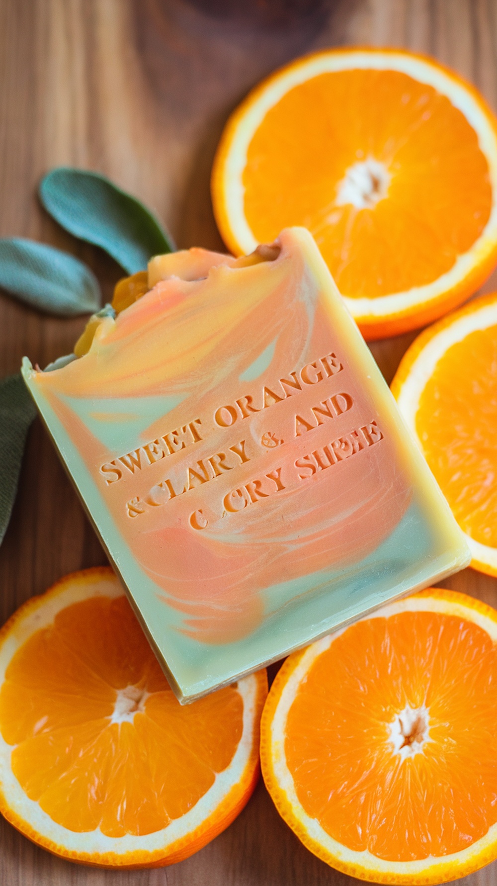 A colorful bar of Sweet Orange and Clary Sage soap next to fresh orange slices.