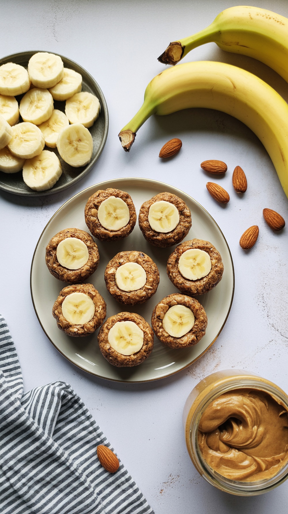 A plate of almond butter and banana energy bites, with sliced bananas and whole bananas nearby.