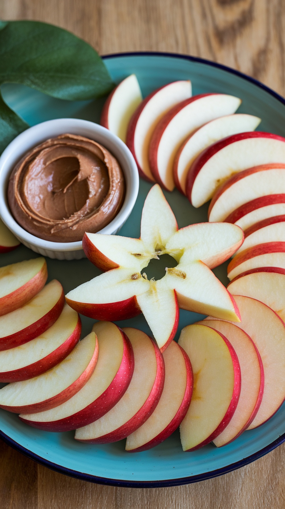 A plate of sliced apples arranged with a bowl of almond butter.