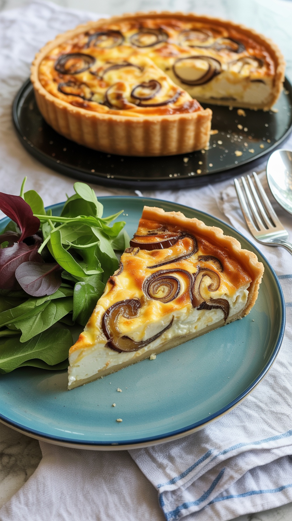 Slice of caramelized onion and goat cheese quiche on a plate with a side salad.