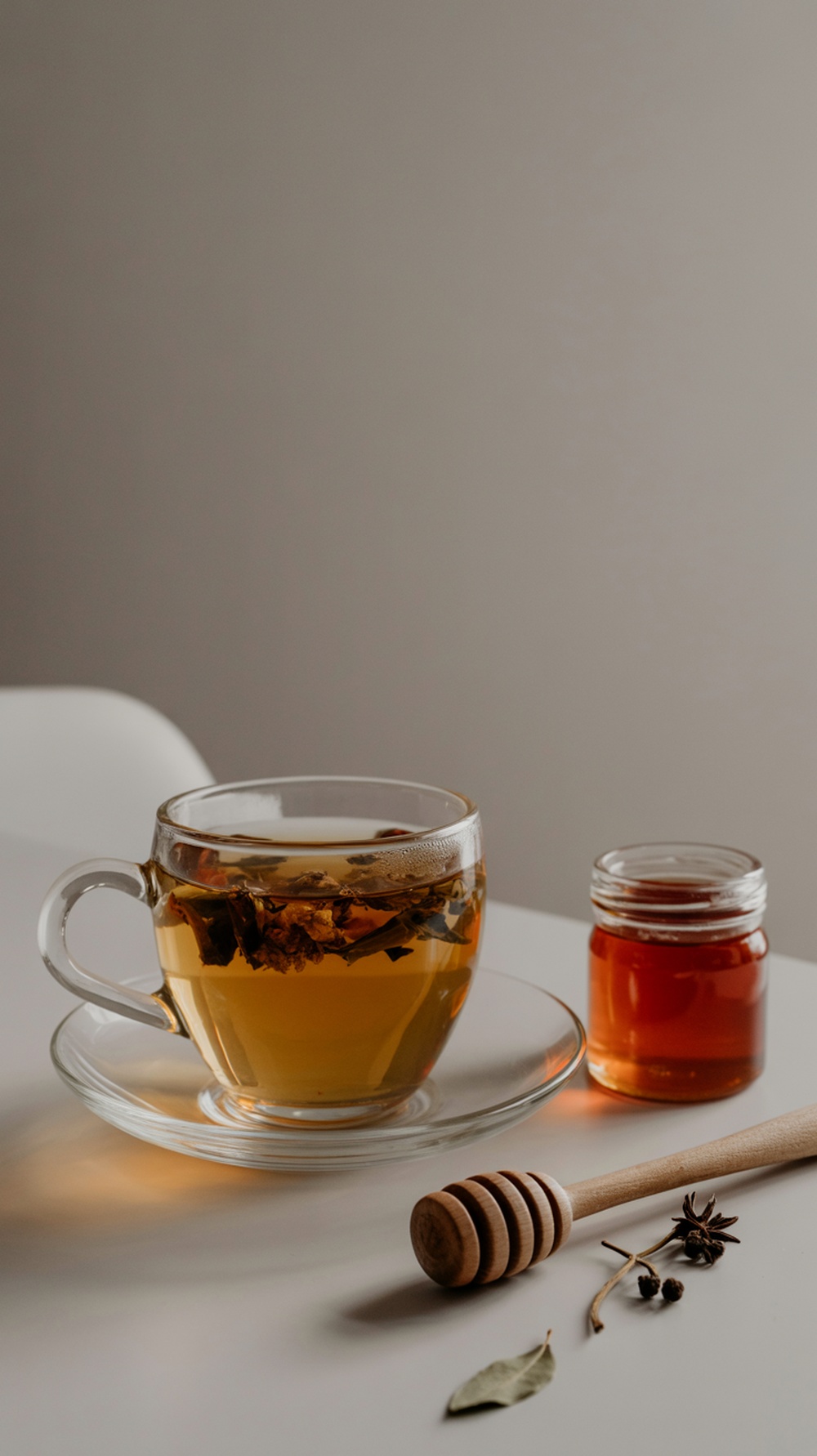 A cup of herbal digestive tea with honey and spices on the side.