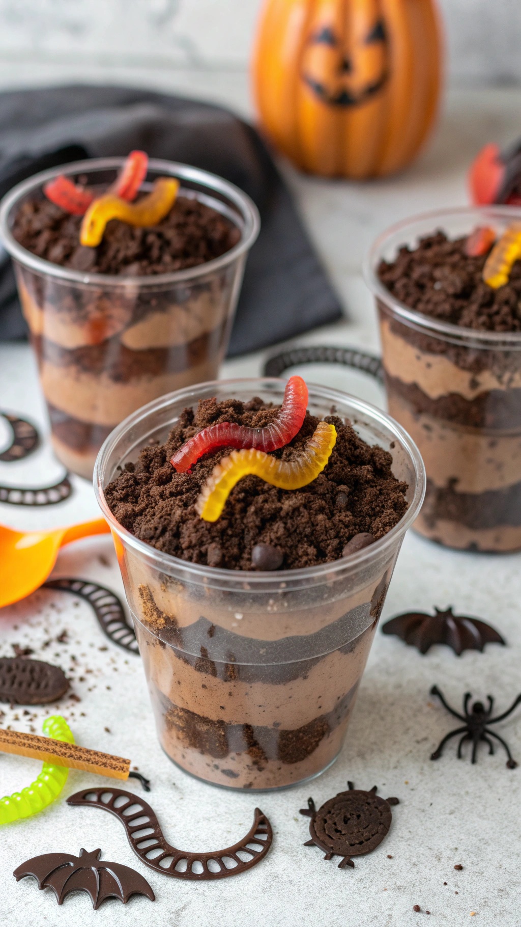 Gummy worm dirt cups with layers of chocolate pudding and crushed Oreos, topped with gummy worms.