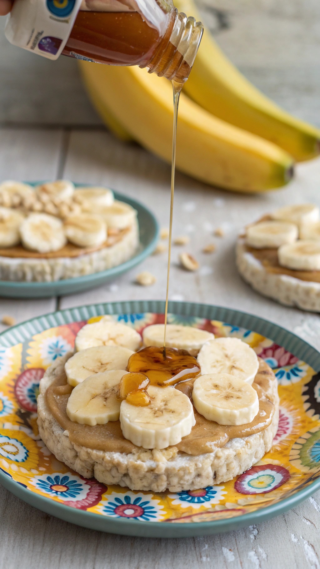 Rice cakes topped with peanut butter and banana slices, with honey being drizzled on top.