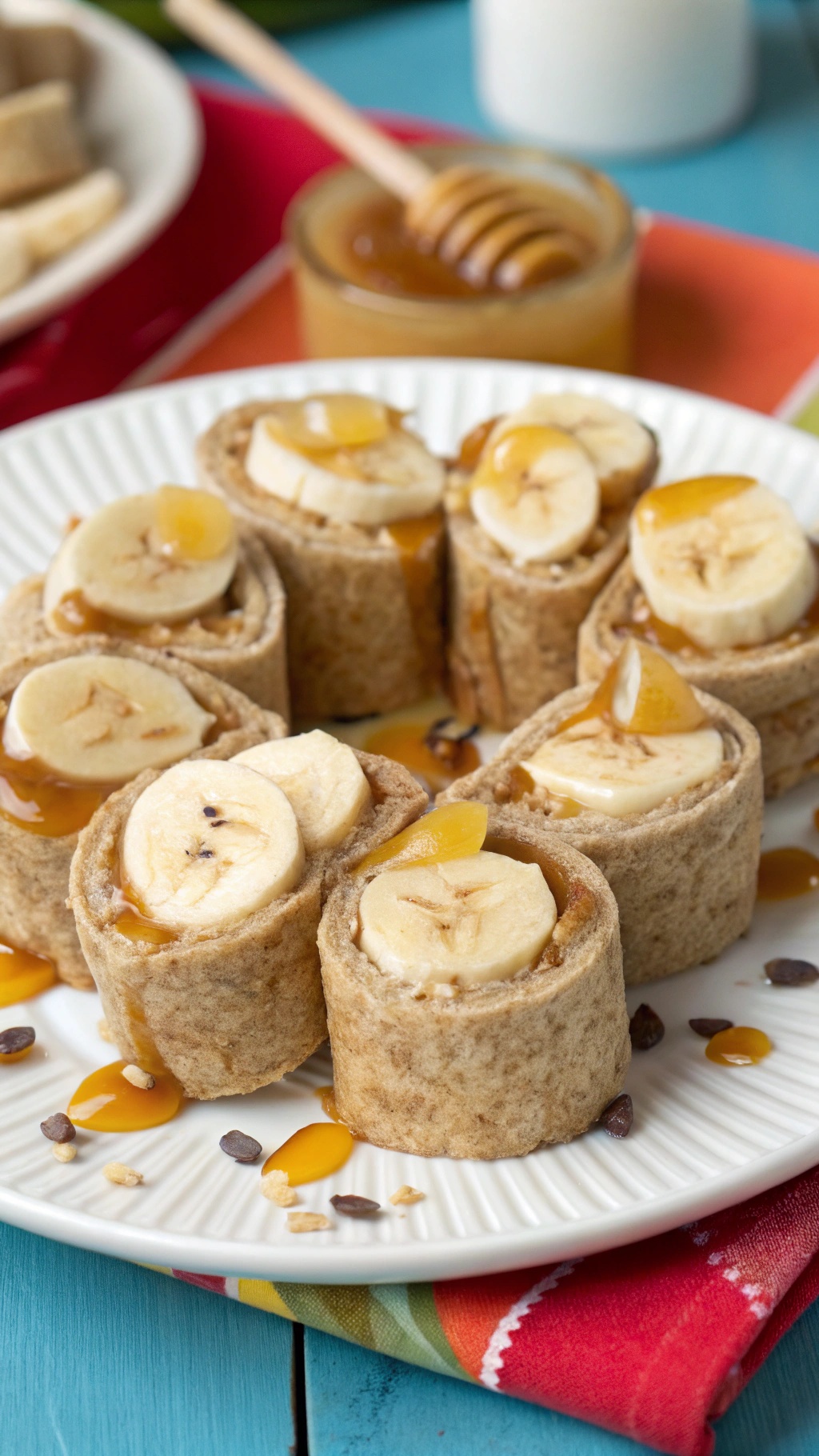 Nut Butter Banana Sushi Rolls on a plate with honey and granola