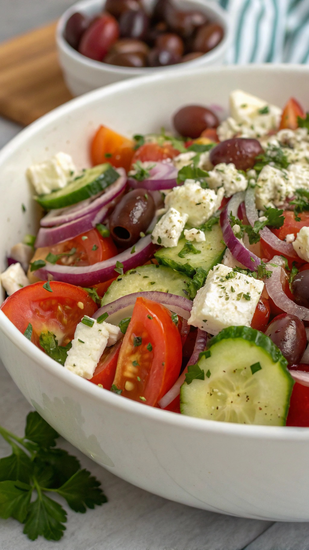 A vibrant Greek salad with feta cheese, tomatoes, cucumbers, olives, and red onions in a large bowl.