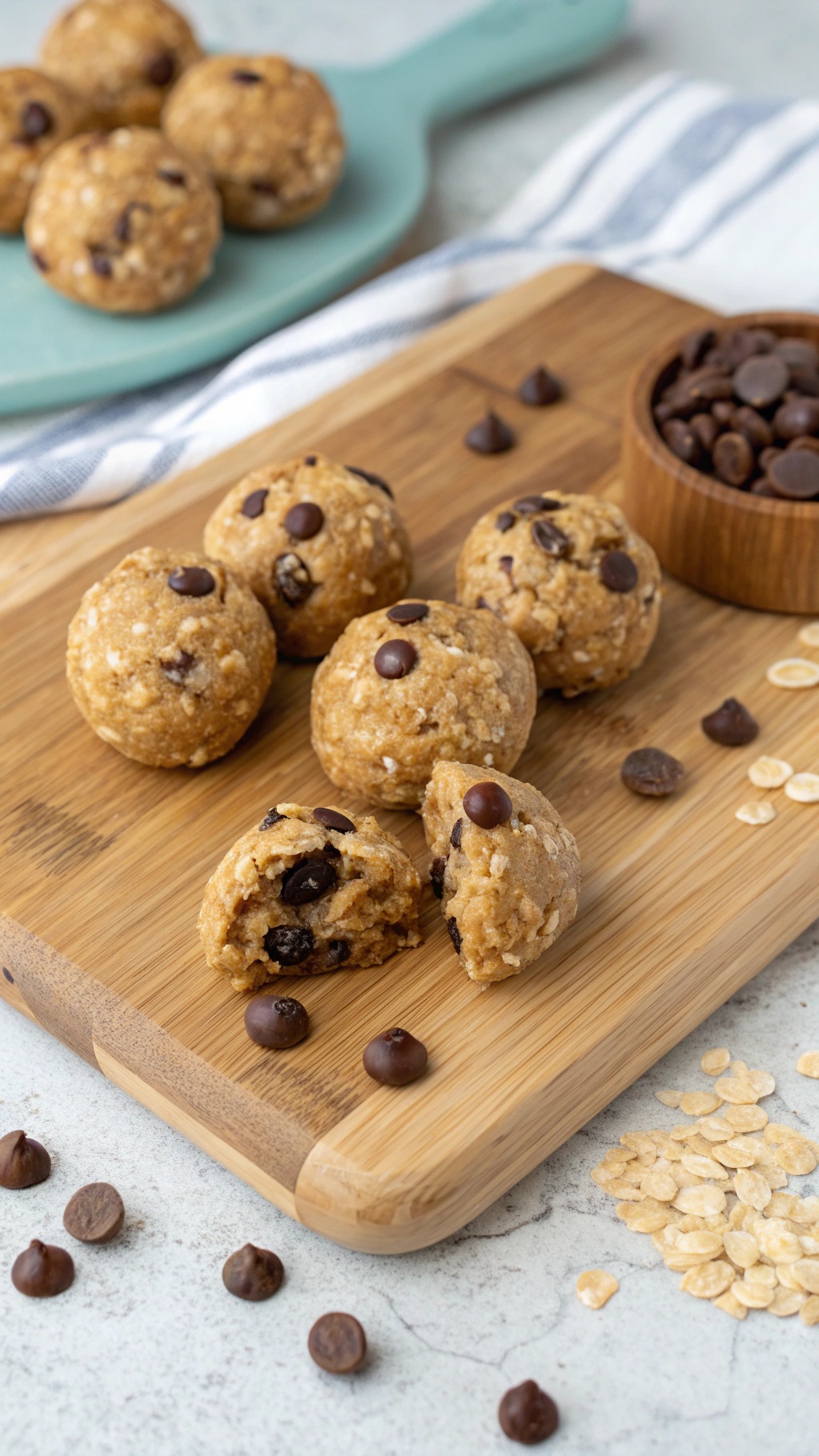 Chocolate Peanut Butter Energy Bites on a wooden board with chocolate chips and oats scattered around.